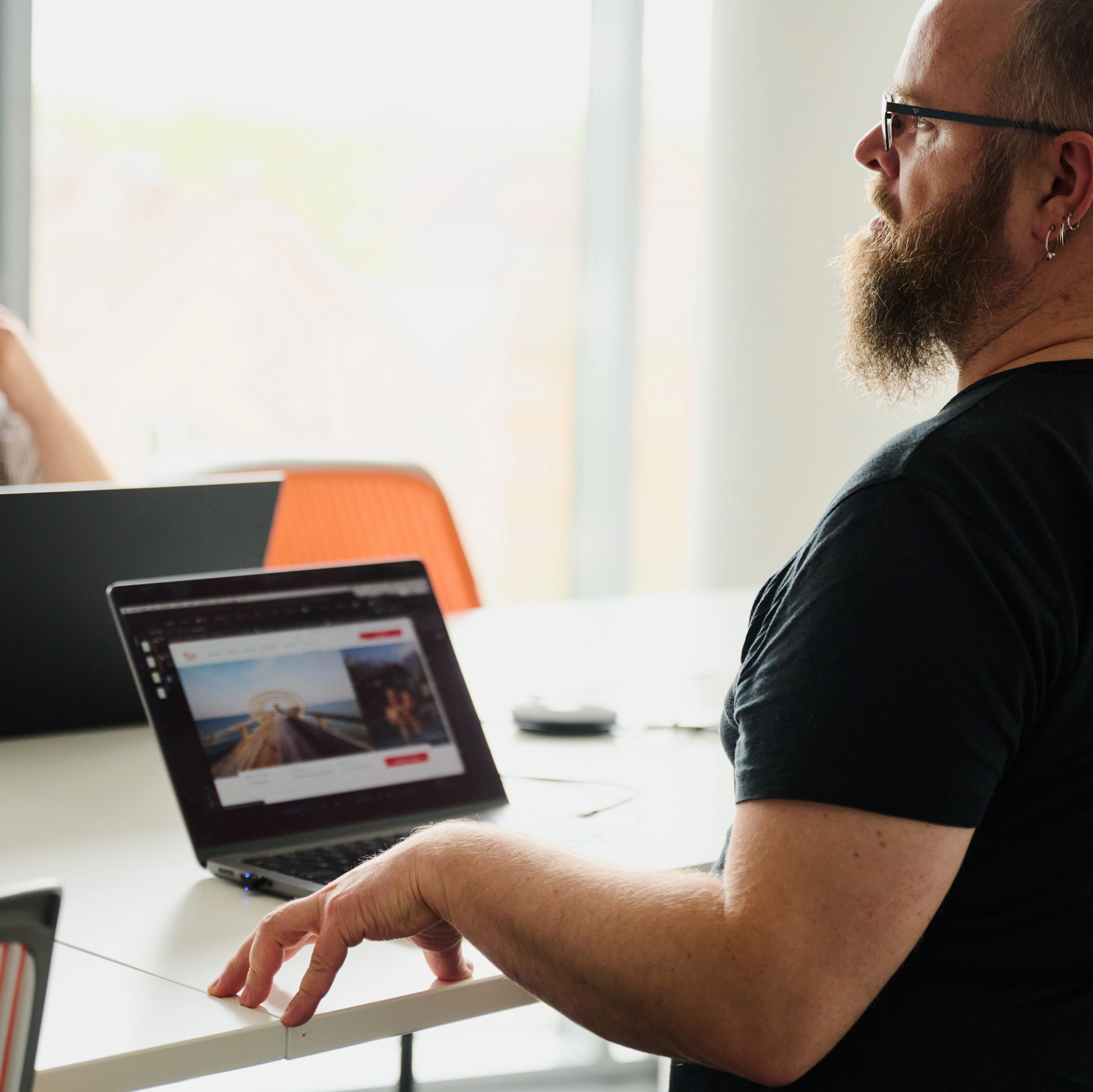 Mann sitzt mit Laptop an einem Tisch.